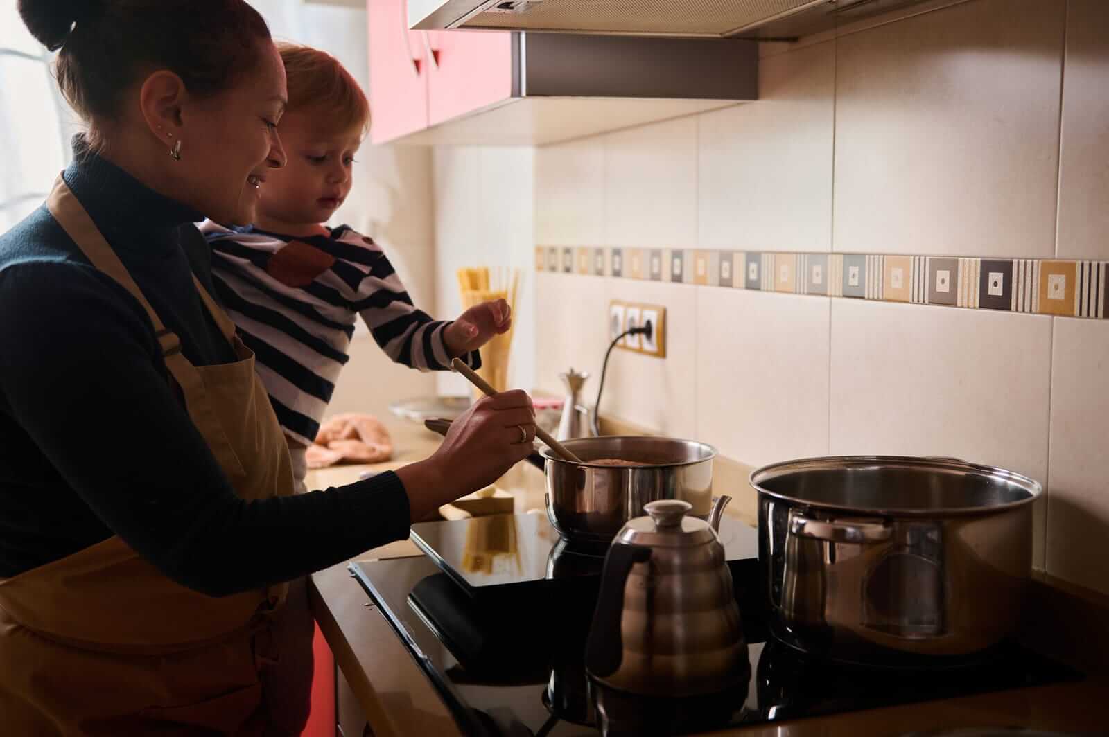 gotująca kobieta w kuchni z dzieckiem na rękach
